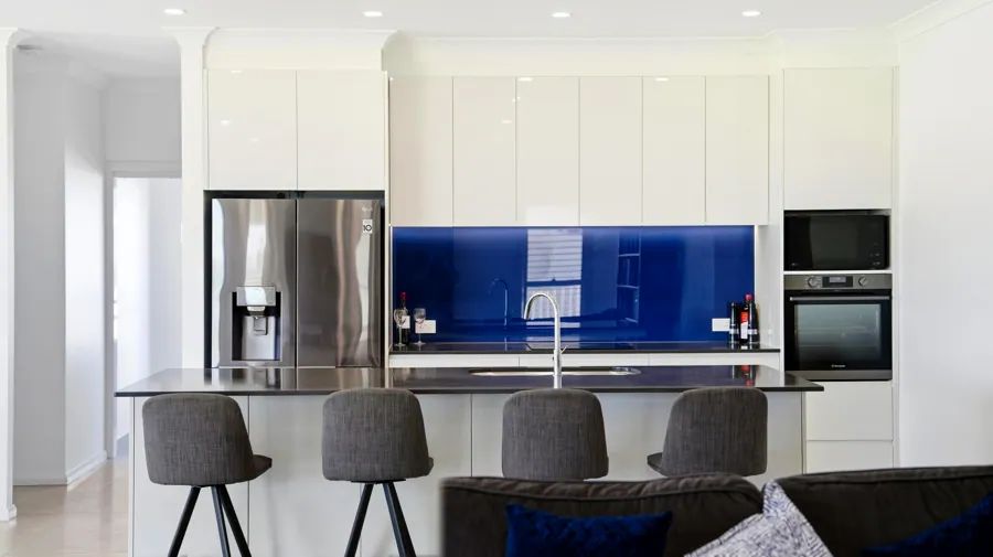 Kitchen island, white cabinetry and blue splashback