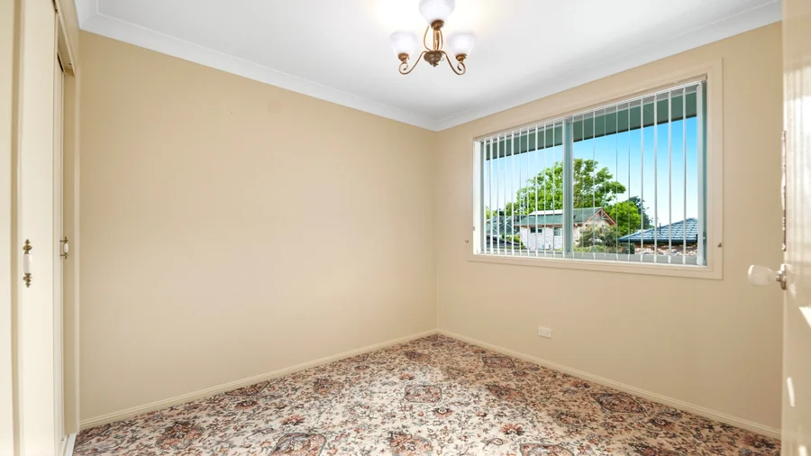 Carpeted bedroom with a window and decorative light