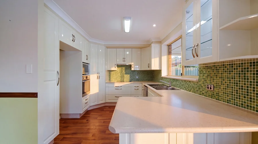 Kitchen with pale cabinetry and green tiled splashback